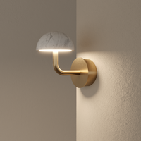 Wandleuchte 'Dussa' von Aromas del Campo aus Messing mit Schirm aus weißem Marmor, moderner Stil, Lifestyle-Aufnahme an beiger Wand mit warmem Lichtschein