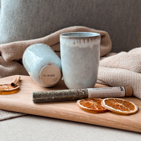 Geschenkset von Tell Me More mit Schneidebrett aus Holz, zwei handgefertigten sandfarbenen Bechern aus Steingut und aromatischen Gewürzen, nachhaltig verpackt