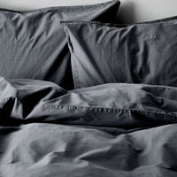 Zwei dunkelgraue Kissenbezüge von Tell Me More aus Bio‑Baumwolle, 65 × 65 cm, mit nachhaltiger Herstellung in Portugal. Wickelverschluss