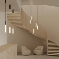 Pendelleuchte 'Ison' schwarz von Aromas del Campo – Gruppe schwarzer Pendel in verschiedenen Längen über geschwungener Sandsteintreppe, warm leuchtende Leuchtkörper, Architektur-Interiorstilshot mit zwei Sesseln