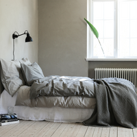 Bettwäsche Set aus Baumwolle von Tell Me More in hellgrau und Dunkelgrau arrangiert auf einem Bett in einer schönen minimalistschen Umgebung