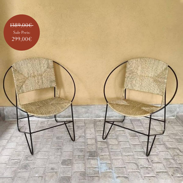 Zweier Set von Stühlen mit Sitz- und Rückenlehne aus Naturfaser und Gestell aus schwarzem Stahl.