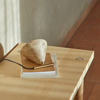 Nahaufnahme der Tischleuchte Iconic von Aromas del Campo, Marmor-Schirm mit goldenem Messing-Sockel auf einem Holztisch mit Terrakottaboden