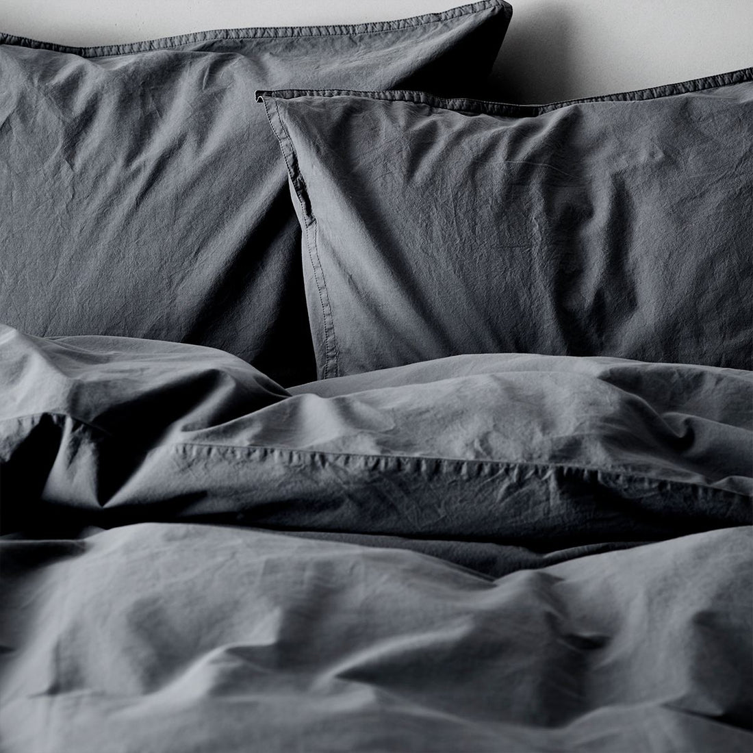 Zwei dunkelgraue Kissenbezüge von Tell Me More aus Bio‑Baumwolle, 65 × 65 cm, mit nachhaltiger Herstellung in Portugal. Wickelverschluss