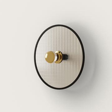 Schöne Wandleuchte 'Lass' von Aromas del Campo. Runder goldfarbener Teller aus Glas mit schwarz gefasstem Rand.