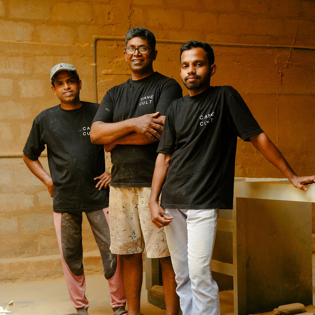 Cane Cult Team in der Möbelwerkstatt – drei Handwerker in schwarzen Cane Cult T-Shirts, Hersteller der handgefertigten Stühle 'Kashmir', nachhaltige Möbelproduktion