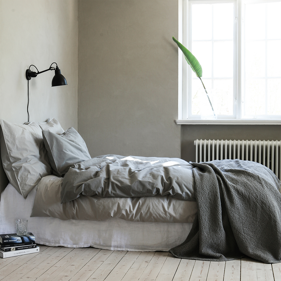 Bettwäsche Set aus Baumwolle von Tell Me More in hellgrau und Dunkelgrau arrangiert auf einem Bett in einer schönen minimalistschen Umgebung